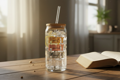 20oz Glass Tumbler with iced water and lemon slice next to open Bible
