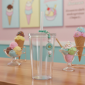 Mint green flower beaded straw charm on a tumbler in a bright colorful ice cream shop setting with pastel walls and ice cream cones